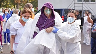Medical staff support a patient breathing through an oxygen mask after a fire in the COVID-19 ICU section of the Hospital for Infectious Diseases in Constanta