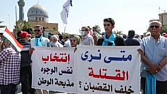 عراقيون يحملون لافتات أثناء مظاهرة في ساحة الفردوس وسط بغداد في 1 تشرين الأول 2021.