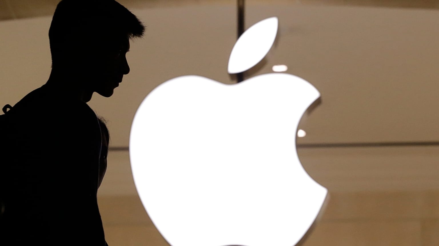 A silhouette of a man standing in front of an Apple store
