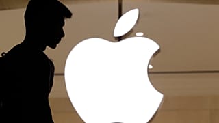 A silhouette of a man standing in front of an Apple store
