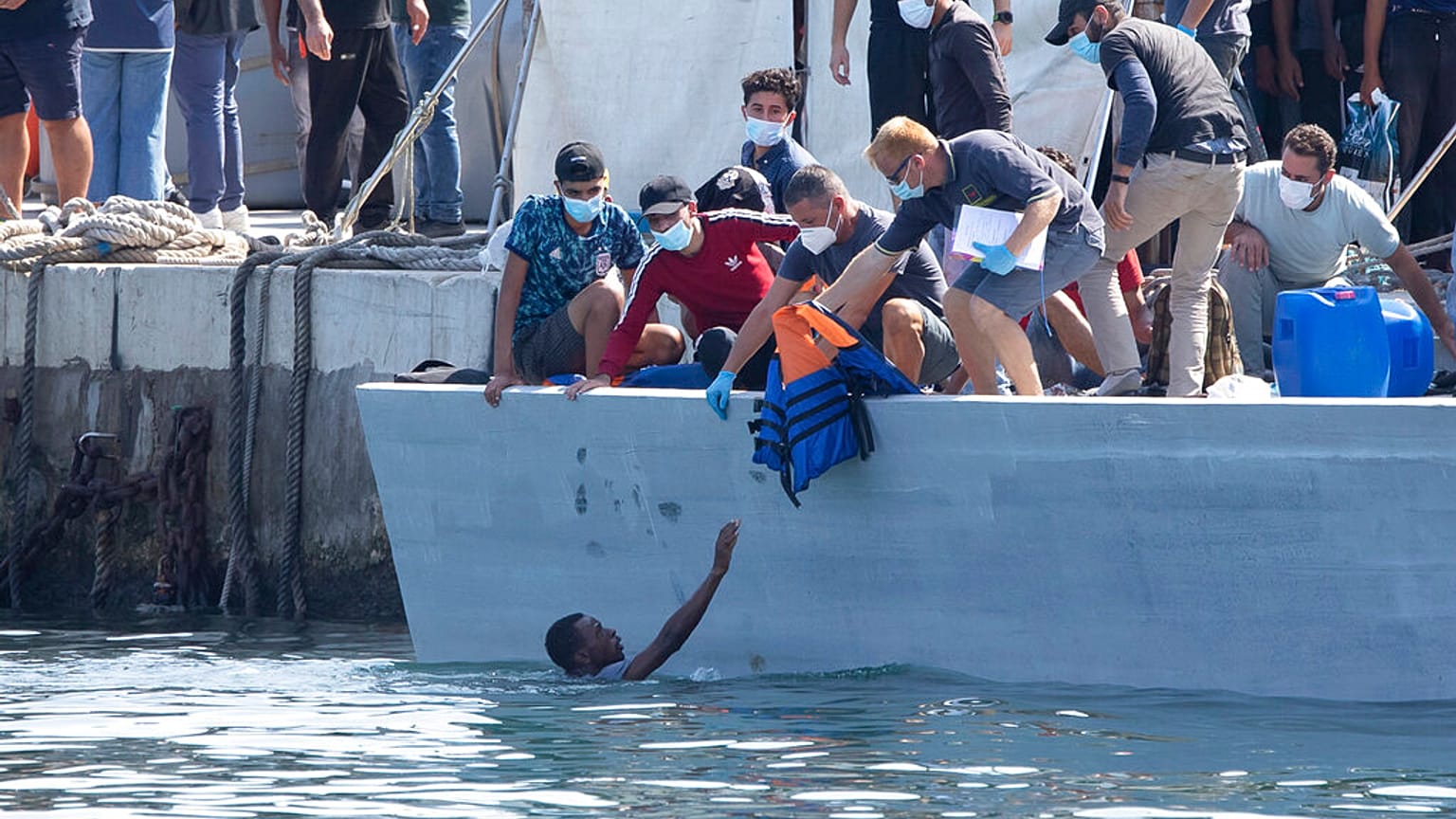 Un homme demande de l'aide, sur l'île italienne de Lampedusa, Italie, le 3 octobre 2021
