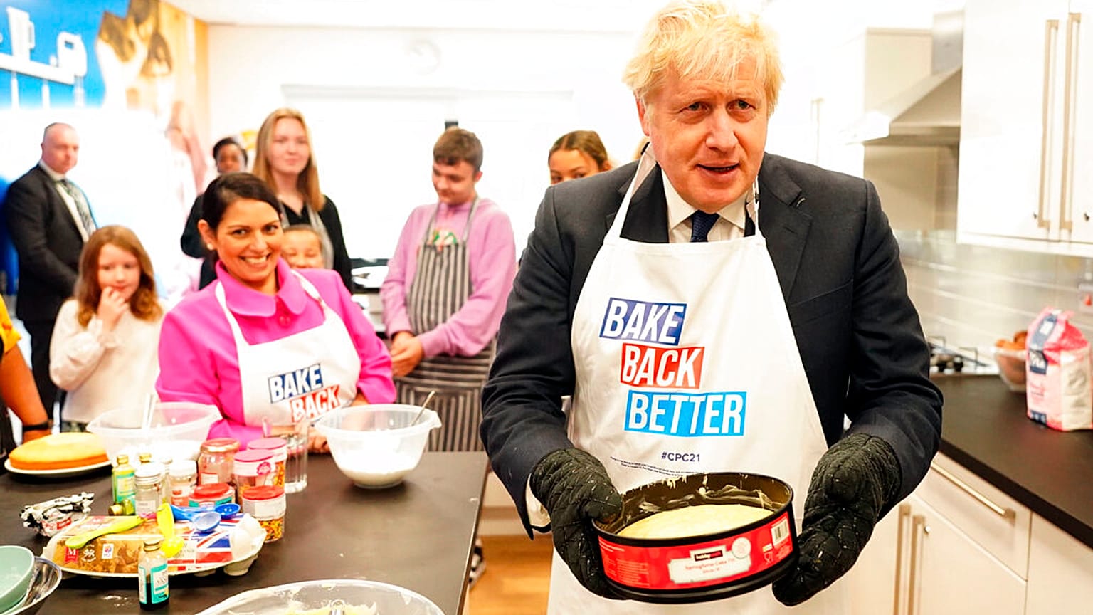 Britain's Prime Minister Boris Johnson and Home Secretary Priti Patel try baking during a visit to HideOut Youth Zone, in Manchester, England, Sunday Oct. 3, 2021.