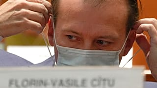 Romanian Prime Minister Florin Citu adjusts his mask ahead of a no confidence vote in Romania's parliament in Bucharest, Romania, Tuesday, Oct. 5, 2021.