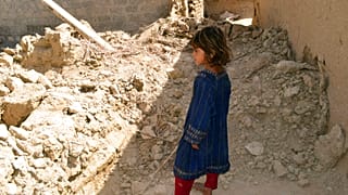Une fillette regardant une maison endommagée après le tremblement de terre à Harnai, à environ 100 kilomètres à l'est de Quetta, au Pakistan, jeudi 7 octobre 2021.