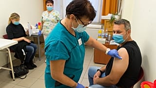 Egy magyar férfi megkapja a Comirnaty-vakcina harmadik, emlékeztető adagját a győri Petz Aladár Megyei Oktató Kórház oltópontján 2021. október 7-én