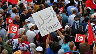 تونسيون يرفعون الأعلام الوطنية خلال مسيرة ضد رئيسهم على طول شارع الحبيب بورقيبة في العاصمة تونس في 10 أكتوبر 2021.