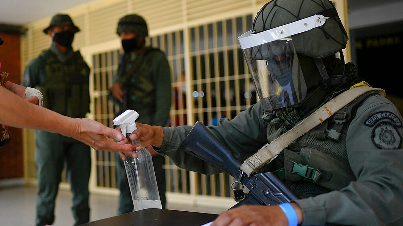 Un soldado echa desinfectante en las manos de un participante en el simulacro electoral en El Valle, Caracas