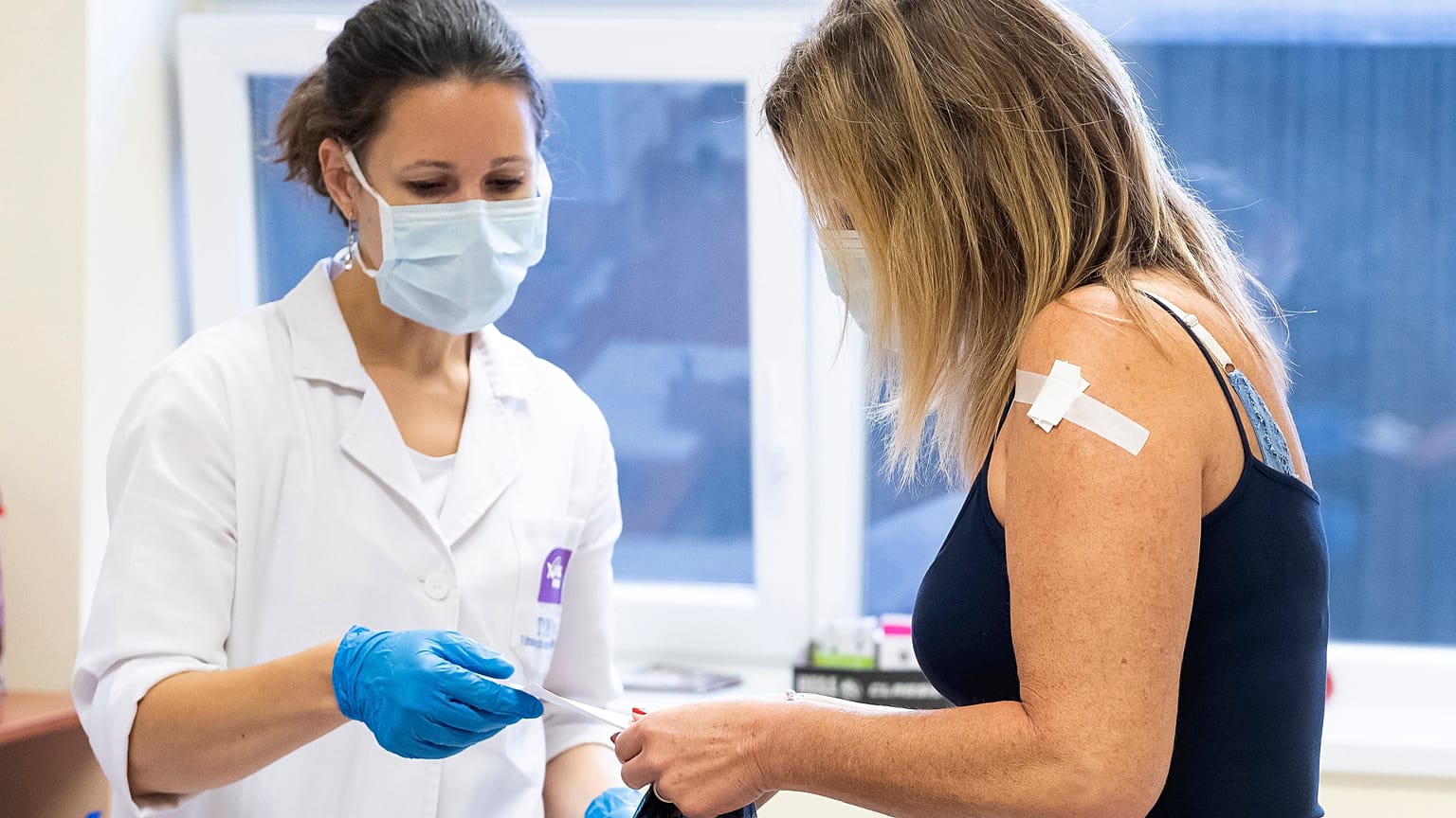 Juhász Tünde tüdőgyógyász szakorvos átadja az oltási igazolást egy nőnek, miután beoltotta a német-amerikai fejlesztésű Pfizer-BioNTech koronavírus elleni oltóanyaggal