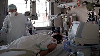 ممرض يعتني بمريضة في وحدة العناية المركزة في مستشفى شارل نيكول، في روان، فرنسا.