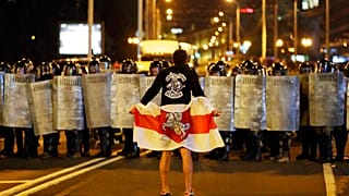  Tarihi Belarus bayrağı tutan bir protestocu polisin önünde duruyor. 9 Ağustos 2020