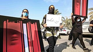 نساء كويتيات يحملن لافتة خلال مسيرة للتنديد بالعنف ضد المرأة، خارج مجلس الأمة، في العاصمة الكويتية، 22 أبريل 2021