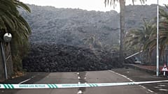 A Spanish Civil Guard tape is seen along a road blocked by lava spewed from the Cumbre Vieja volcano in La Laguna
