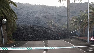 A Spanish Civil Guard tape is seen along a road blocked by lava spewed from the Cumbre Vieja volcano in La Laguna