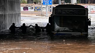 Passengers wade through high water after evacuating a bus stuck in a flooded underpass in southern Athens.