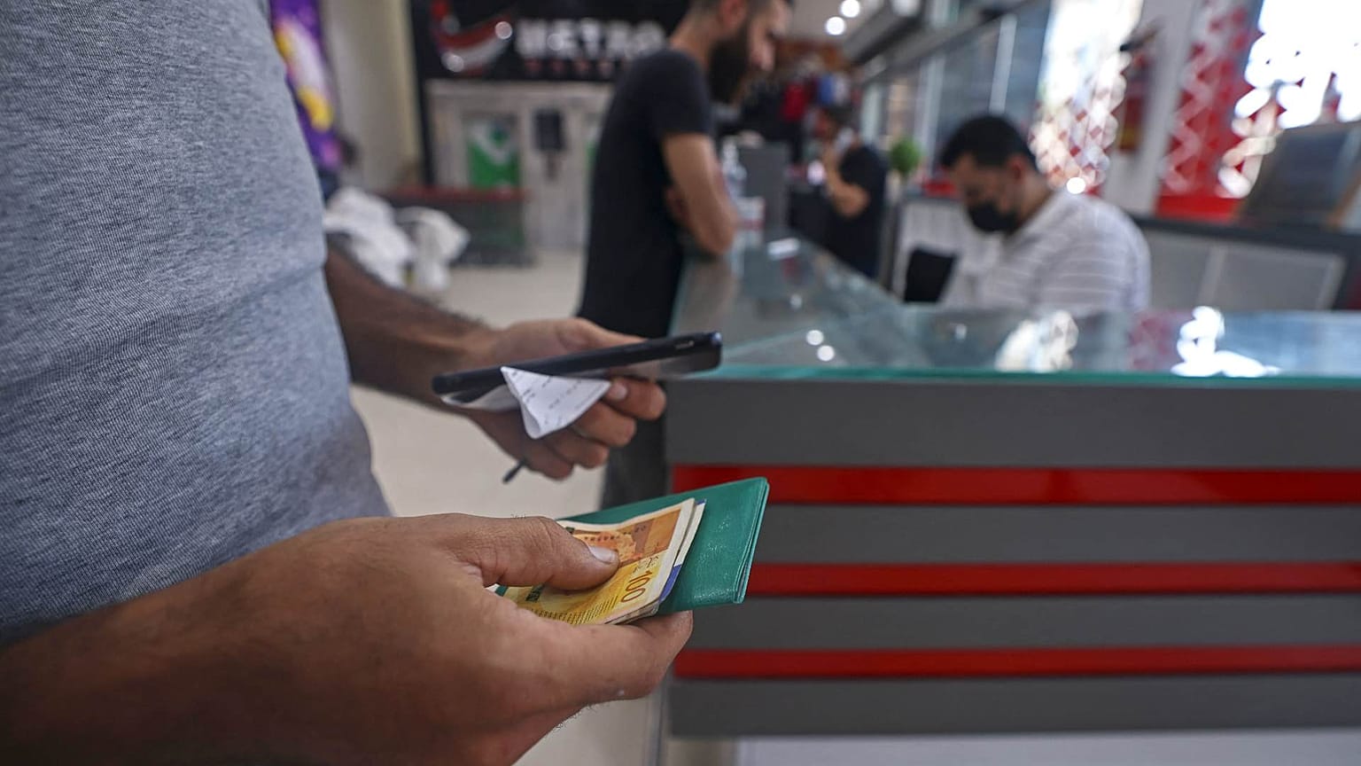 رجل فلسطيني يتلقى مساعدة مالية في سوبر ماركت في مدينة غزة كدعم من دولة قطر، 15 سبتمبر 2021 