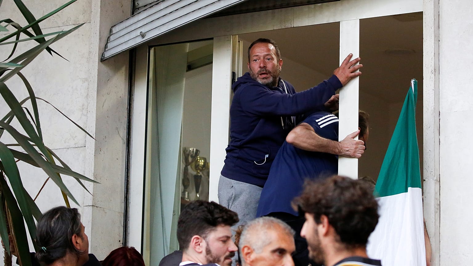 Demonstrators climb through a window outside the CGIL (Italian General Confederation of Labour) union during an anti-Green Pass protest 