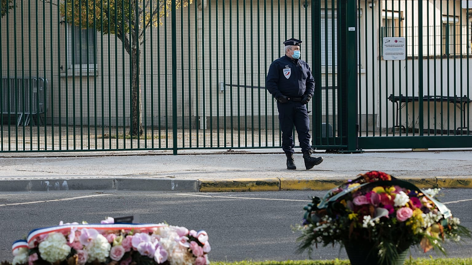 Floral tributes are left in front of the school where teacher Samuel Paty worked, in Conflans Sainte Honorine, Friday, Oct. 15, 2021.