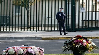 Floral tributes are left in front of the school where teacher Samuel Paty worked, in Conflans Sainte Honorine, Friday, Oct. 15, 2021.