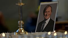 Candles are lit next to a portrait of British Lawmaker David Amess during a vigil for him at St Michaels Church, in Leigh-on-Sea, England Sunday, Oct. 17, 2021.