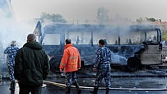 In this photo released by the Syrian official news agency SANA, Syrian firefighters and security officer check a burned bus