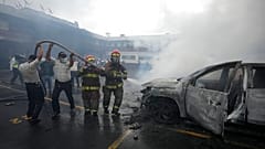 Los bomberos y la policía colaboran para sofocar con agua un vehículo incendiado, 19/10/2021, Guatemala, Guatemala