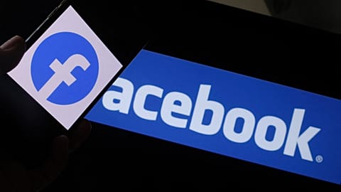 Facebook logo on a smartphone in front of a computer screen
