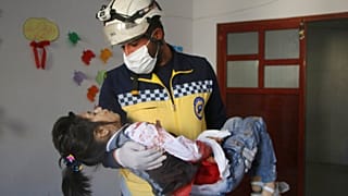 Un casco blanco de la Defensa Civil siria lleva en brazos a una niña herida en el bombardeo