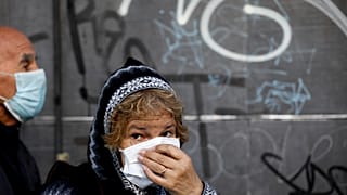 A woman, wearing a protective face mask, waits in line outside a bank, 4/4/2020, Buenos Aires, Argentina