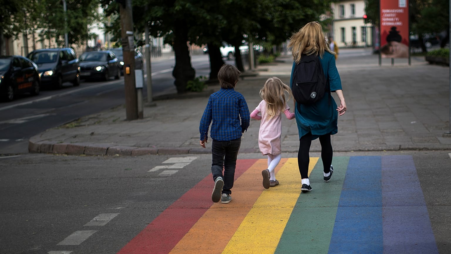 A woman and children walk on a pedestrian crossing painted in the colours of the rainbow flag, a symbol of the gay rights movement in Vilnius, Lithuania.