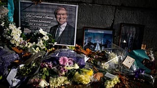 Floral tributes and pictures of British MP David Amess outside the Houses of Parliament in London.