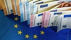 Euro banknotes are displayed next to an European Union flag / FILE PHOTO