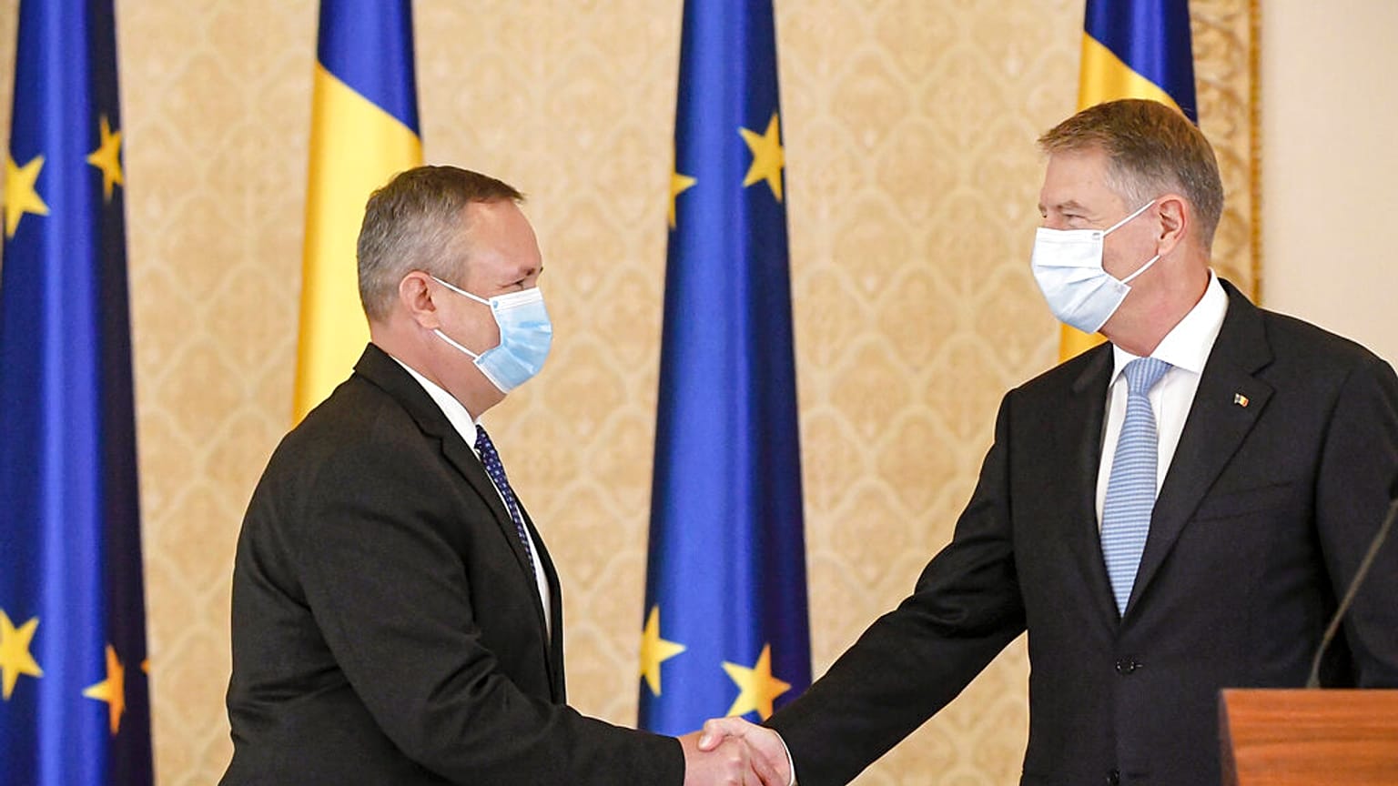 Nicolae Ciuca (izquierda) da la mano al presidente rumano, Klaus Iohannis