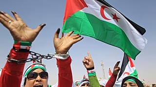 لاجئات من الصحراء الغربية يلوحن بعلمهن غير الرسمي في مخيم للاجئين في تندوف، جنوب الجزائر.