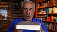 محمد سالم النوري ينفض الغبار عن كتاب في مكتبة دار المعرفة، التي اضطر لإغلاقها عام 2000 بسبب ضعف المبيعات وتزايد التكاليف، في العاصمة السورية دمشق، في 12 أكتوبر 2021
