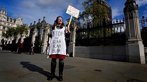 A lone climate demonstrator holds a banner outside parliament in London ahead of COP26.