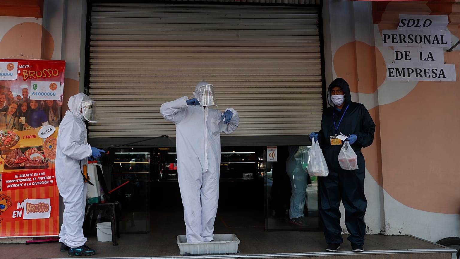An employee dressed in full protection gear steps into a tub of disinfectant for feet, amid the new coronavirus pandemic, in La Paz, Bolivia, Friday, May, 15, 2021.
