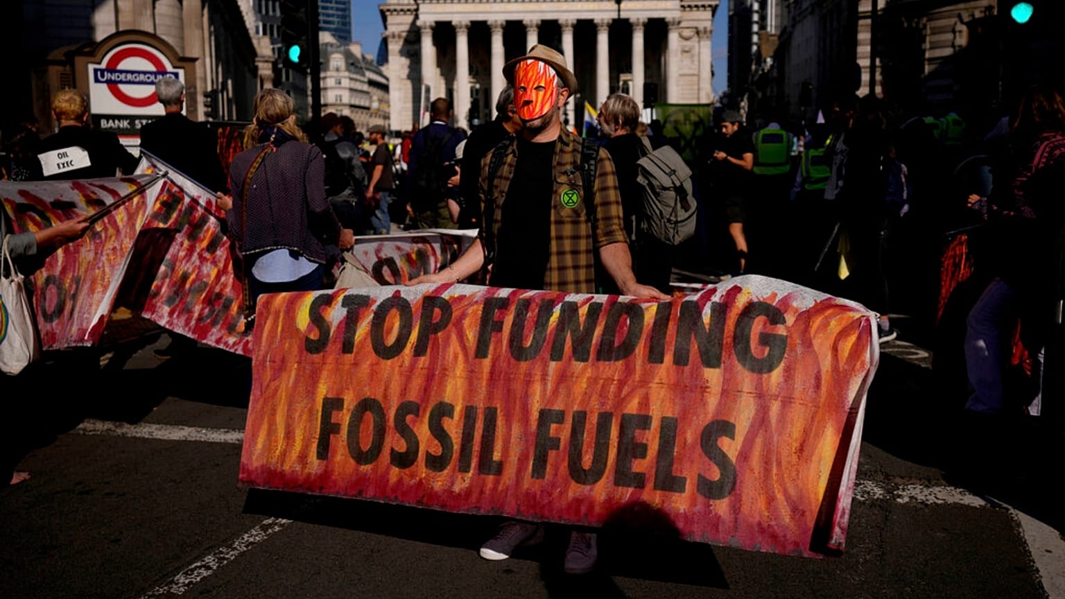 climate change activist holds a banner backdropped by the City of London financial district.