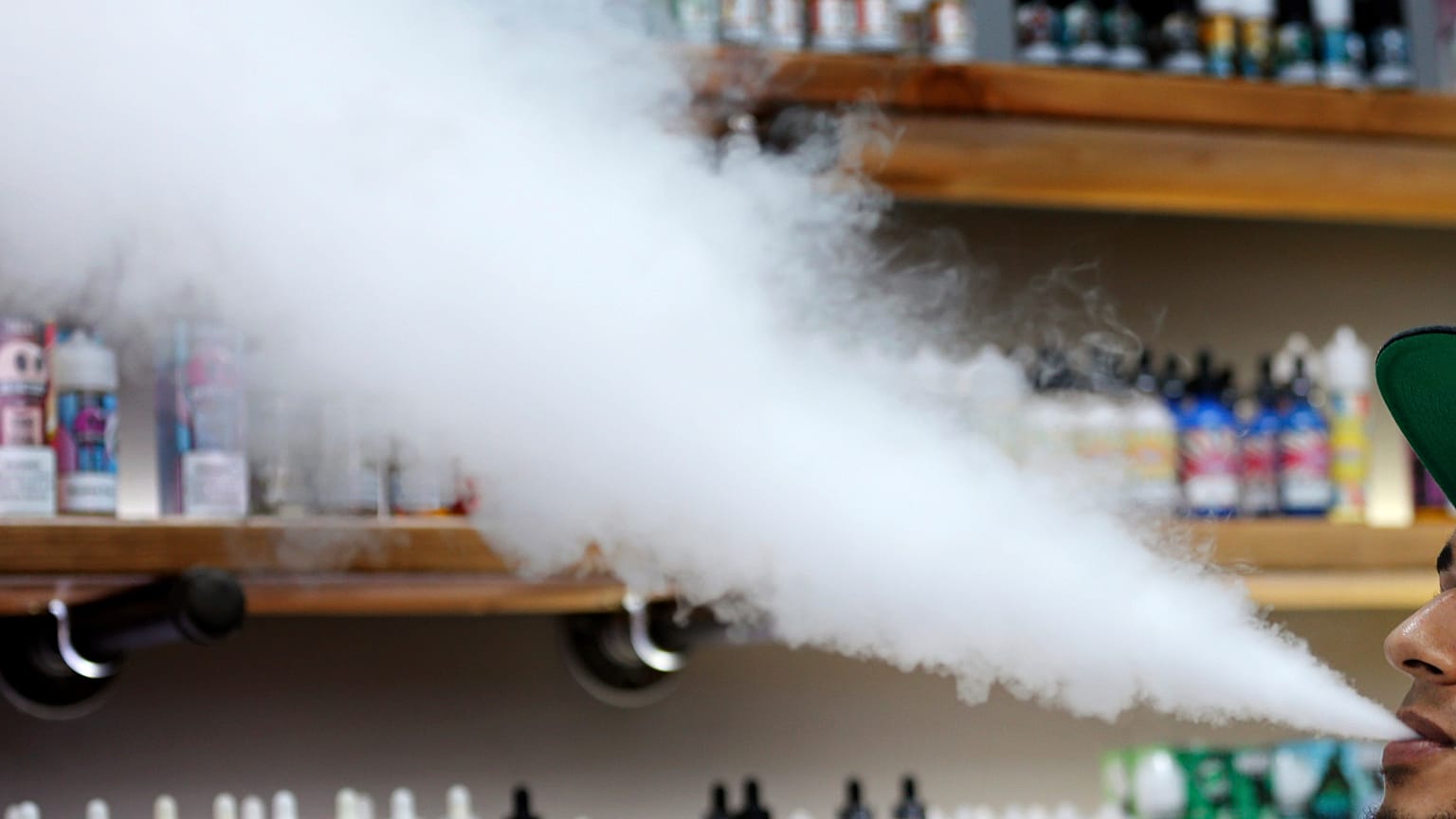 In this Tuesday, Sept. 3, 2019 file photo, a salesman at a vape shop exhales while using an e-cigarette in Maine.