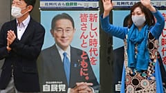 A supporter of Japan's governing Liberal Democratic Party waves by posters of the party president, Japanese Prime Minister Fumio Kishida, Tokyo, Wednesday, Oct. 27, 2021. 