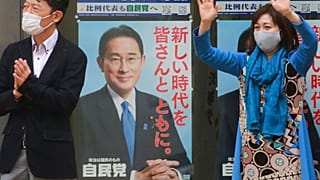 A supporter of Japan's governing Liberal Democratic Party waves by posters of the party president, Japanese Prime Minister Fumio Kishida, Tokyo, Wednesday, Oct. 27, 2021.