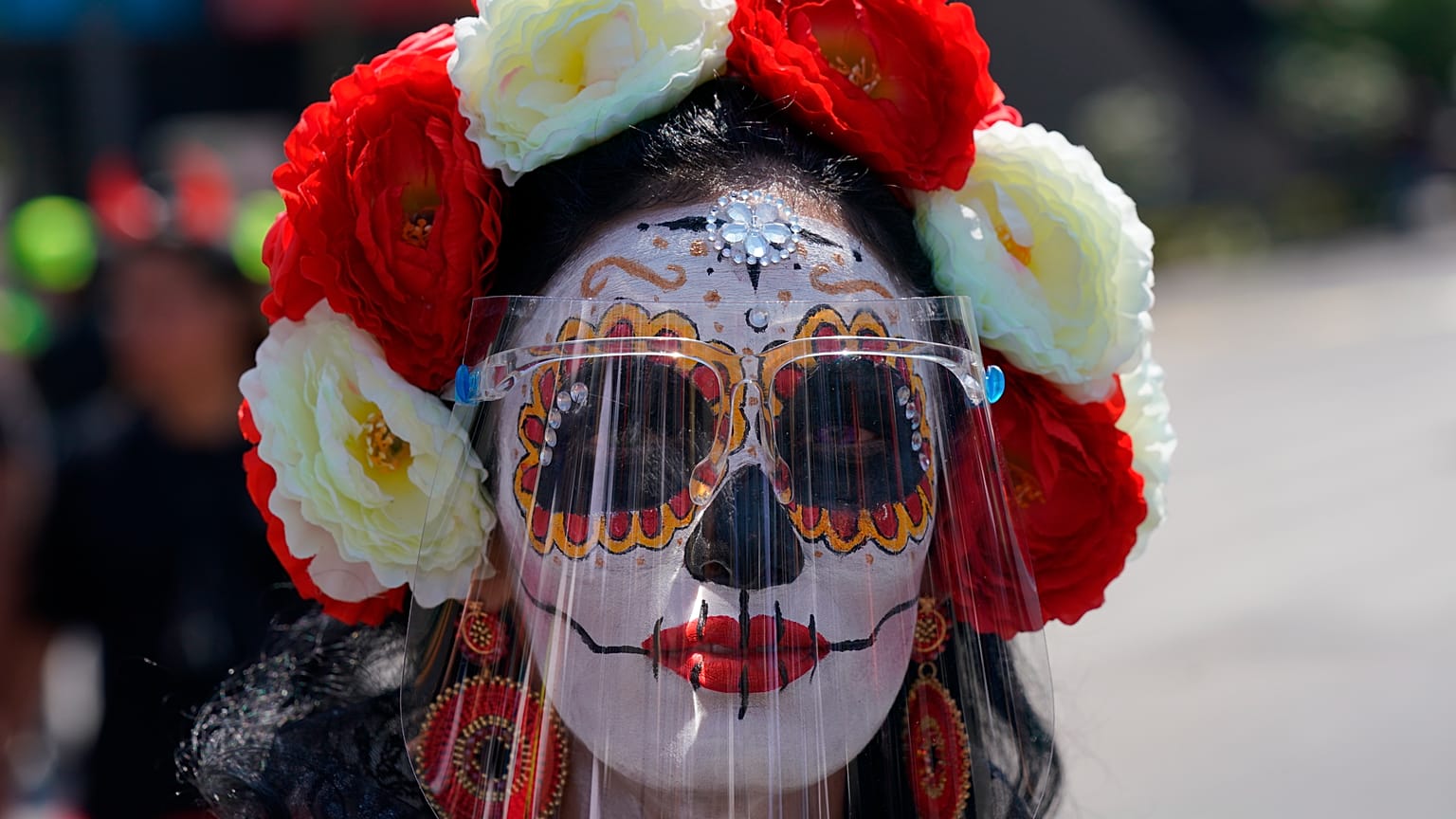 Una mujer disfrazada de "Catrina" y con una pantalla facial posa para una foto durante las festividades del Día de Muertos en la Ciudad de México, el 31 de octubre de 2021.