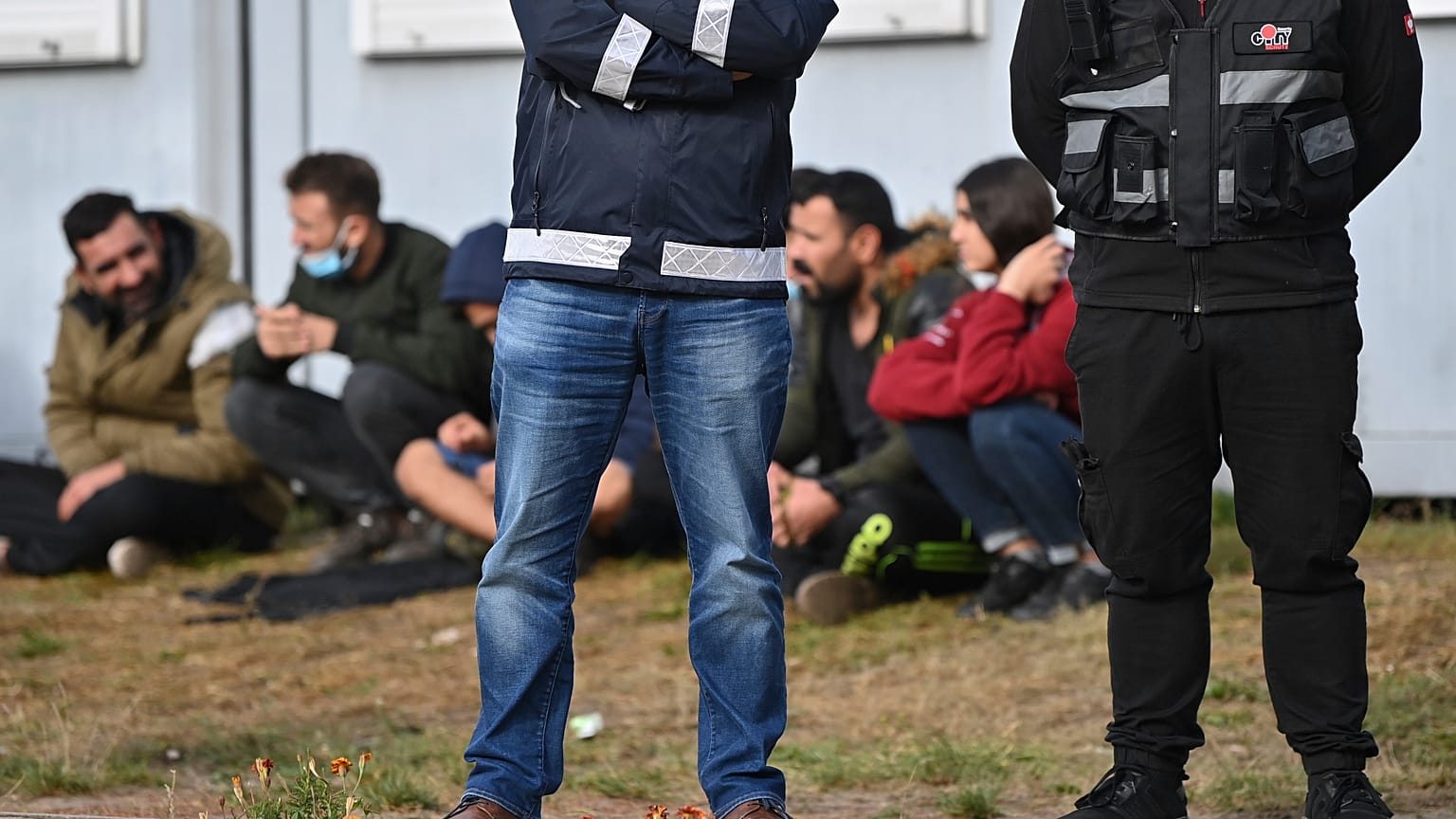 Security guards stand in front of migrants at an asylum facility in Eisenhuettenstadt.