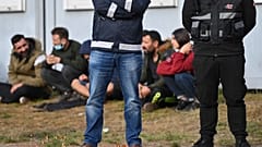 Security guards stand in front of migrants at an asylum facility in Eisenhuettenstadt.