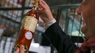 An unidentified auction goer displays a bottle of 1966 Chateau d'Yquem premier cru Sauternes put on auction by the French presidential Palace. File: May 2013