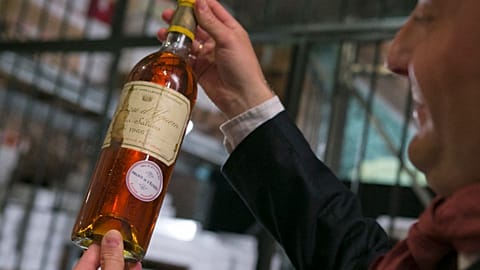 An unidentified auction goer displays a bottle of 1966 Chateau d'Yquem premier cru Sauternes put on auction by the French presidential Palace. File: May 2013