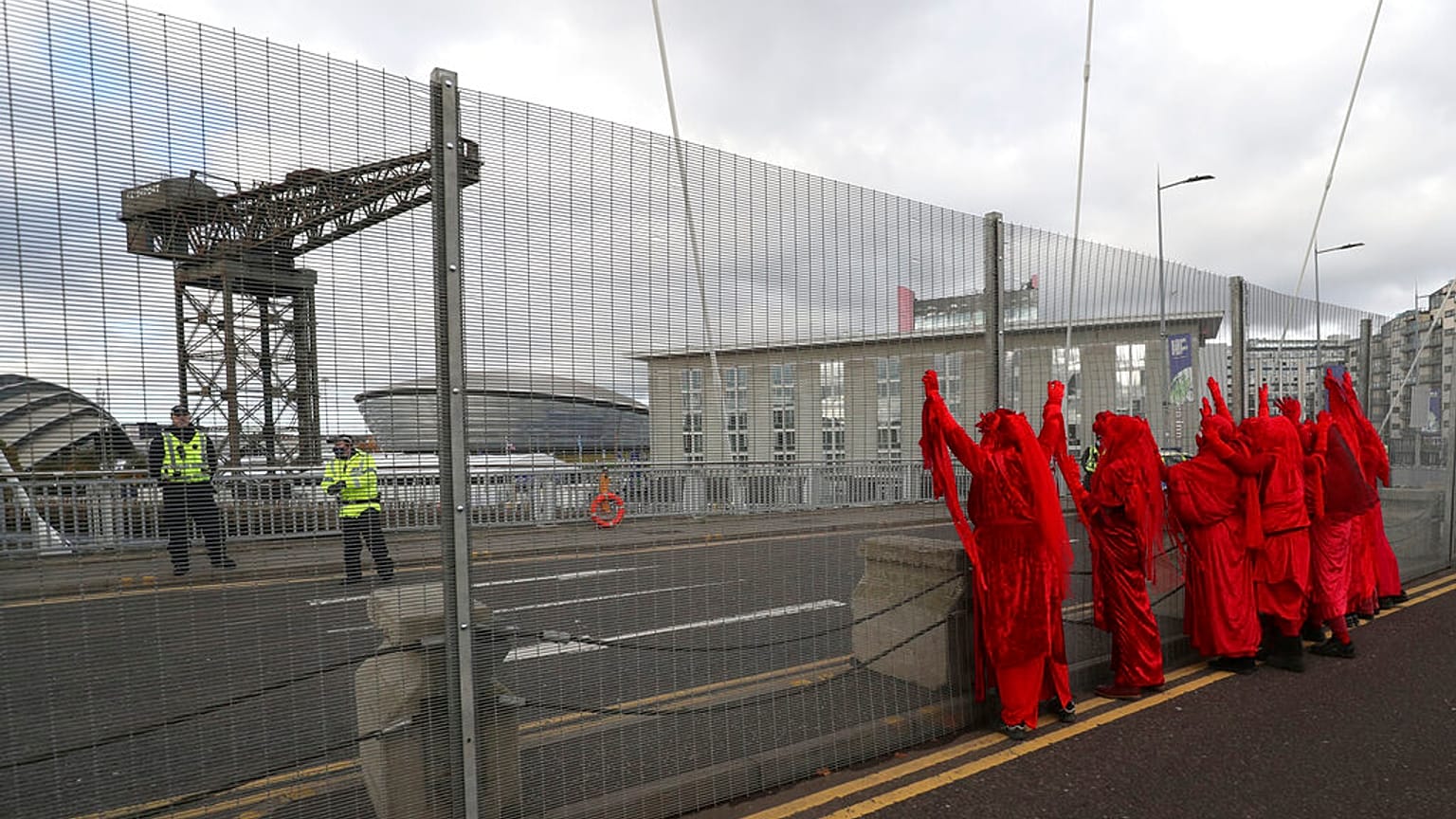 Red Rebel Brigade climate protesters demonstrate by the security fencing outside the Scottish Event Campus, the venue for the COP26 U.N. Climate Summit in Glasgow, on Tuesday