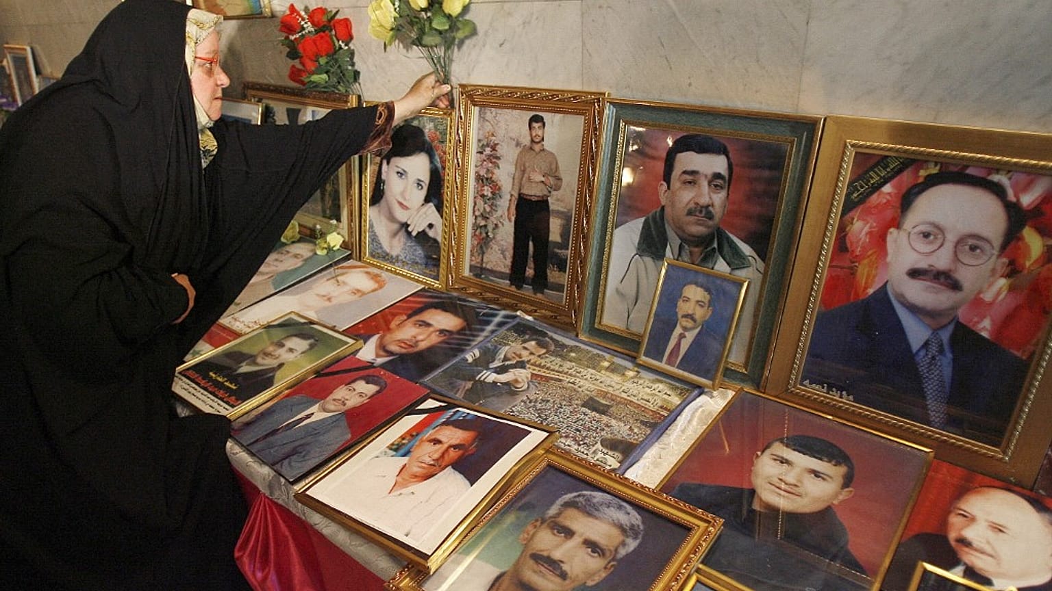 Une femme irakienne dépose des fleurs à côté de photos encadrées de journalistes irakiens tués en Irak en 2007.