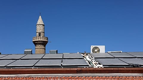 تُظهر هذه الصورة الألواح الشمسية أمام مئذنة مسجد على سطح منزل قبرصي تقليدي في قرية كالافاسوس في منطقة لارنكا، 7 أكتوبر 2021