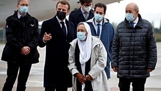 France's President Emmanuel Macron, centre left, and Foreign Minister Jean-Yves Le Drian (R), welcome Sophie Petronin, centre, near Paris, Oct. 9, 2020. 