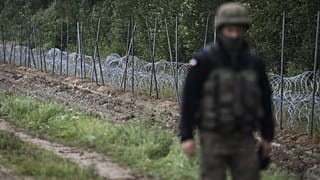 A Polish soldier walks past a barbed wire fence on the border with Belarus in Zubrzyca Wielka.